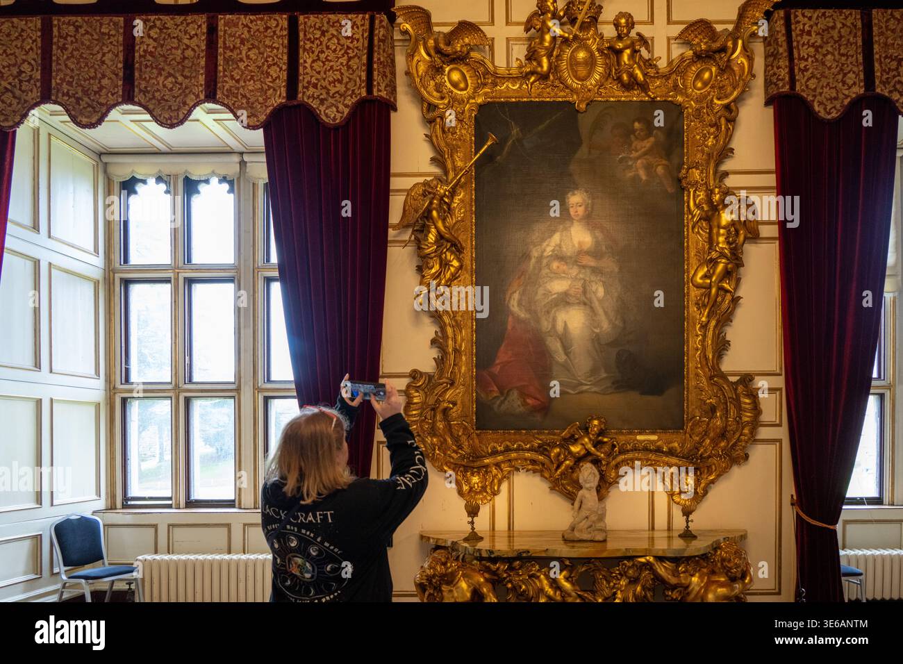 Warwick, Regno Unito - 12 aprile 24: Il turista fotografa un grande ritratto dorato incorniciato in un'elegante sala del castello di Warwick. Foto Stock