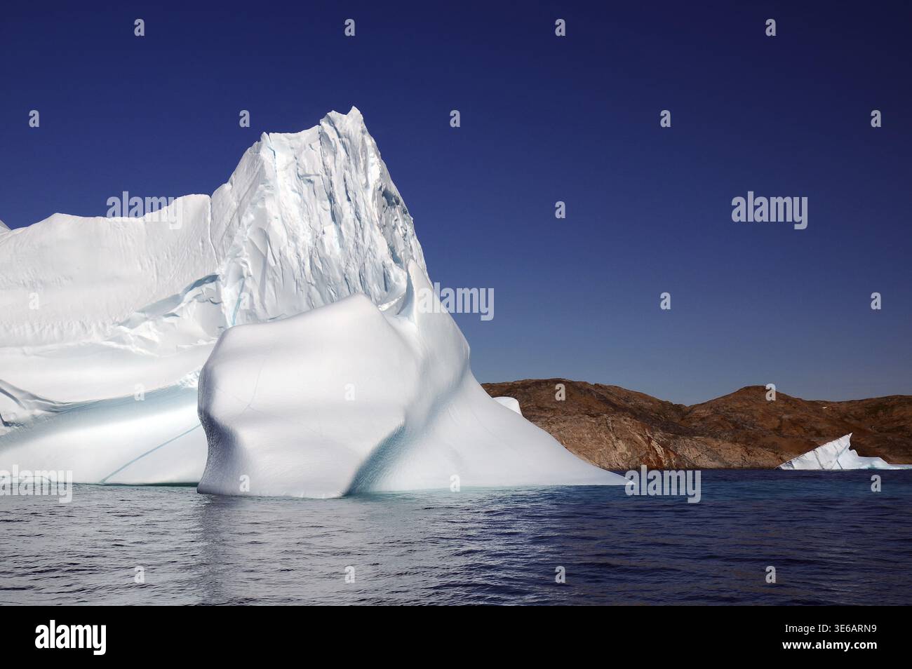 Un imponente iceberg in acque cristalline sotto un cielo senza nuvole, Tasilaq, Artico, Groenlandia, Danimarca Foto Stock
