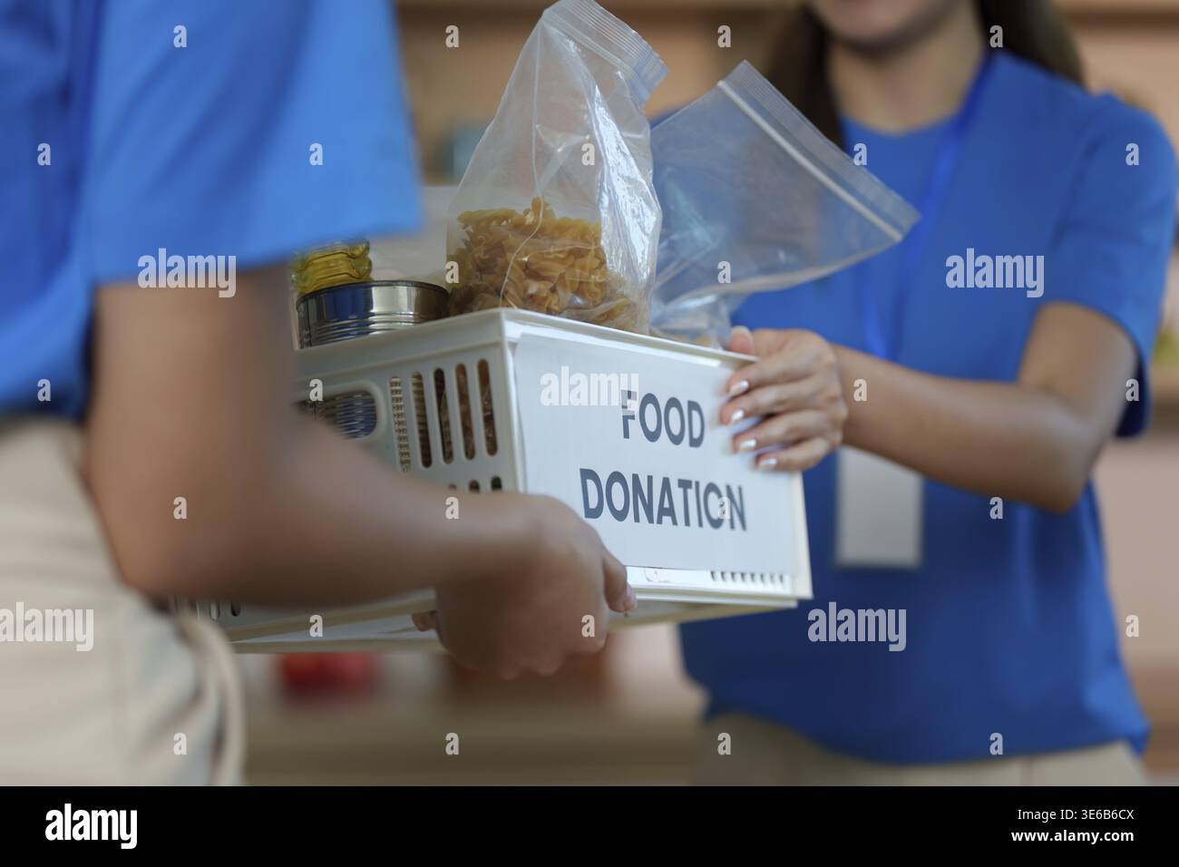 Un volontario presenta una scatola di donazione di cibo, mettendo in evidenza lo spirito di donazione e il coinvolgimento della comunità in azioni di beneficenza Foto Stock