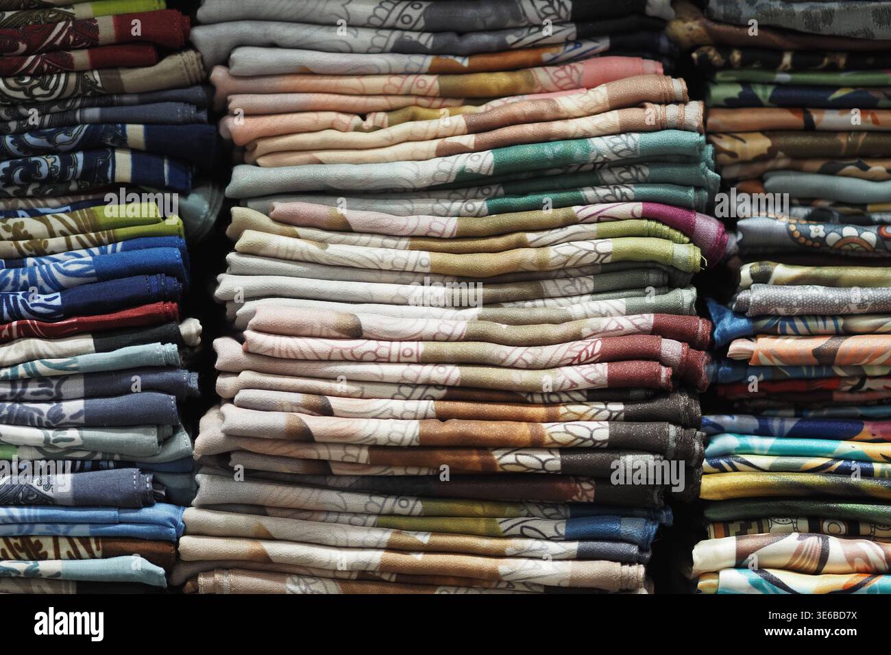 Tessuti colorati impilati ordinatamente in mostra allo stand del mercato Foto Stock