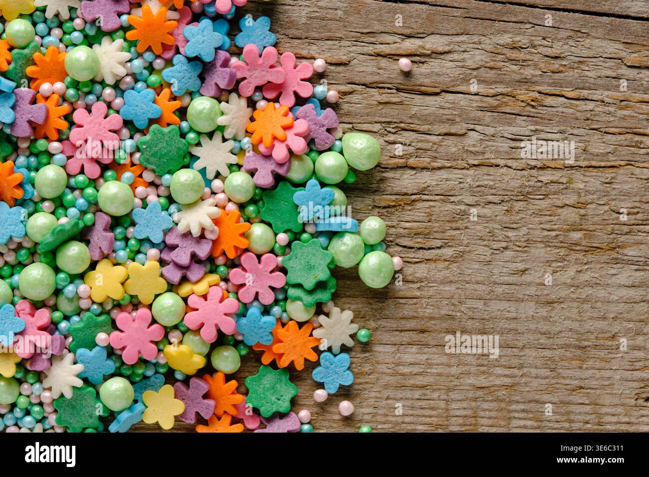 Le caramelle a forma di fiore pastello cospargono su una superficie in legno con spazio per copiare il disegno o il testo, vista dall'alto Foto Stock