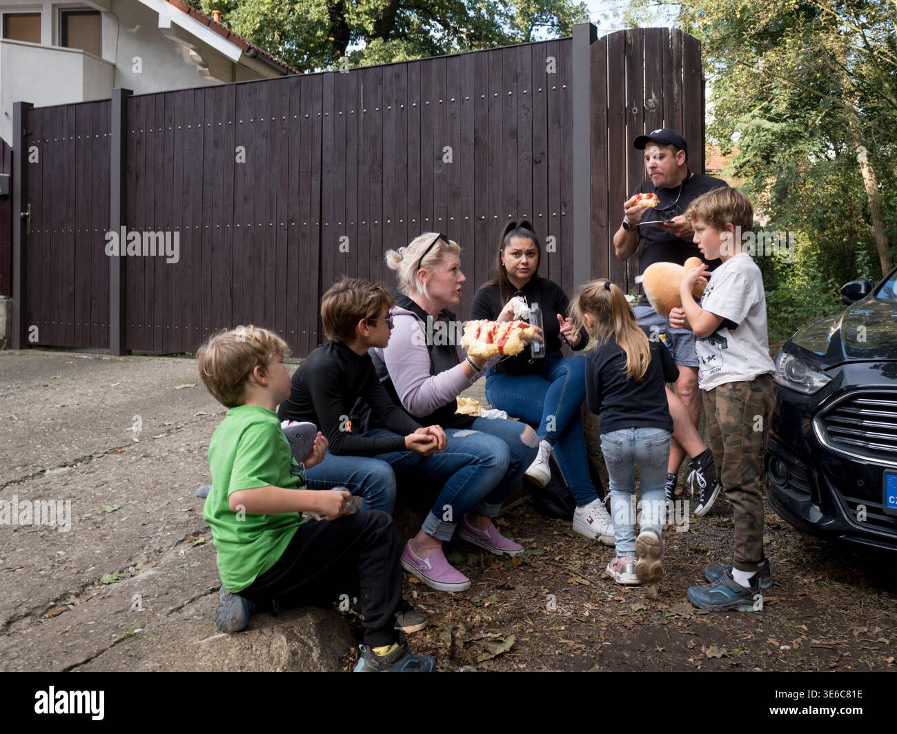 Famiglie con bambini che mangiano hot dog e spuntini in auto durante una sosta in auto o un evento all'aperto Foto Stock