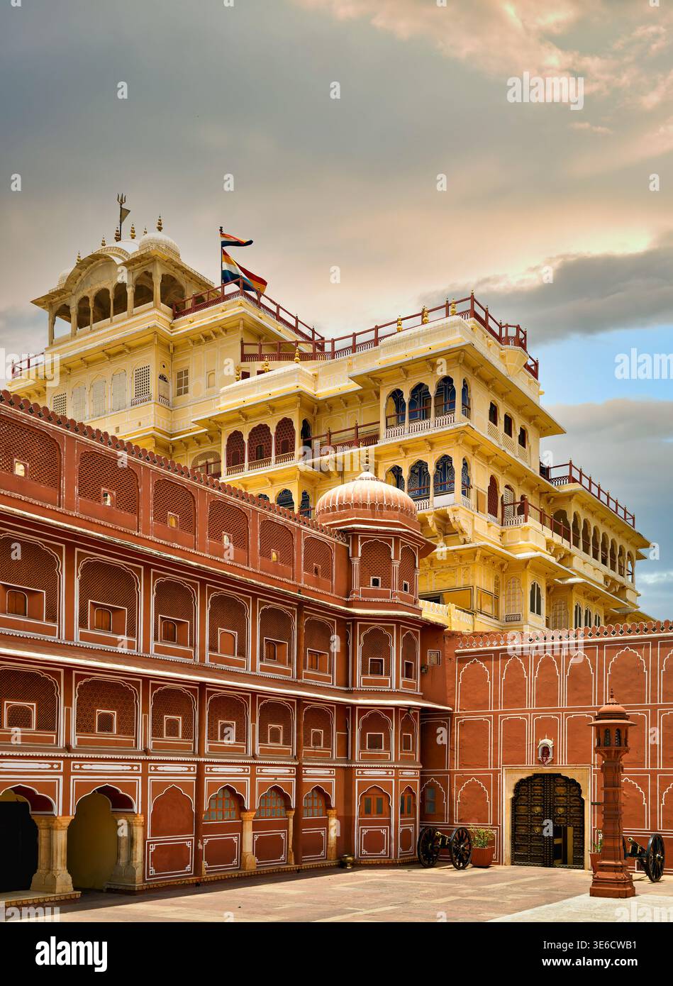 La magnifica facciata di Chandra Mahal al al City Palace Jaipur, Rajasthan, presenta arenaria rossa e ornamenti gialli sotto un cielo nuvoloso. Foto Stock