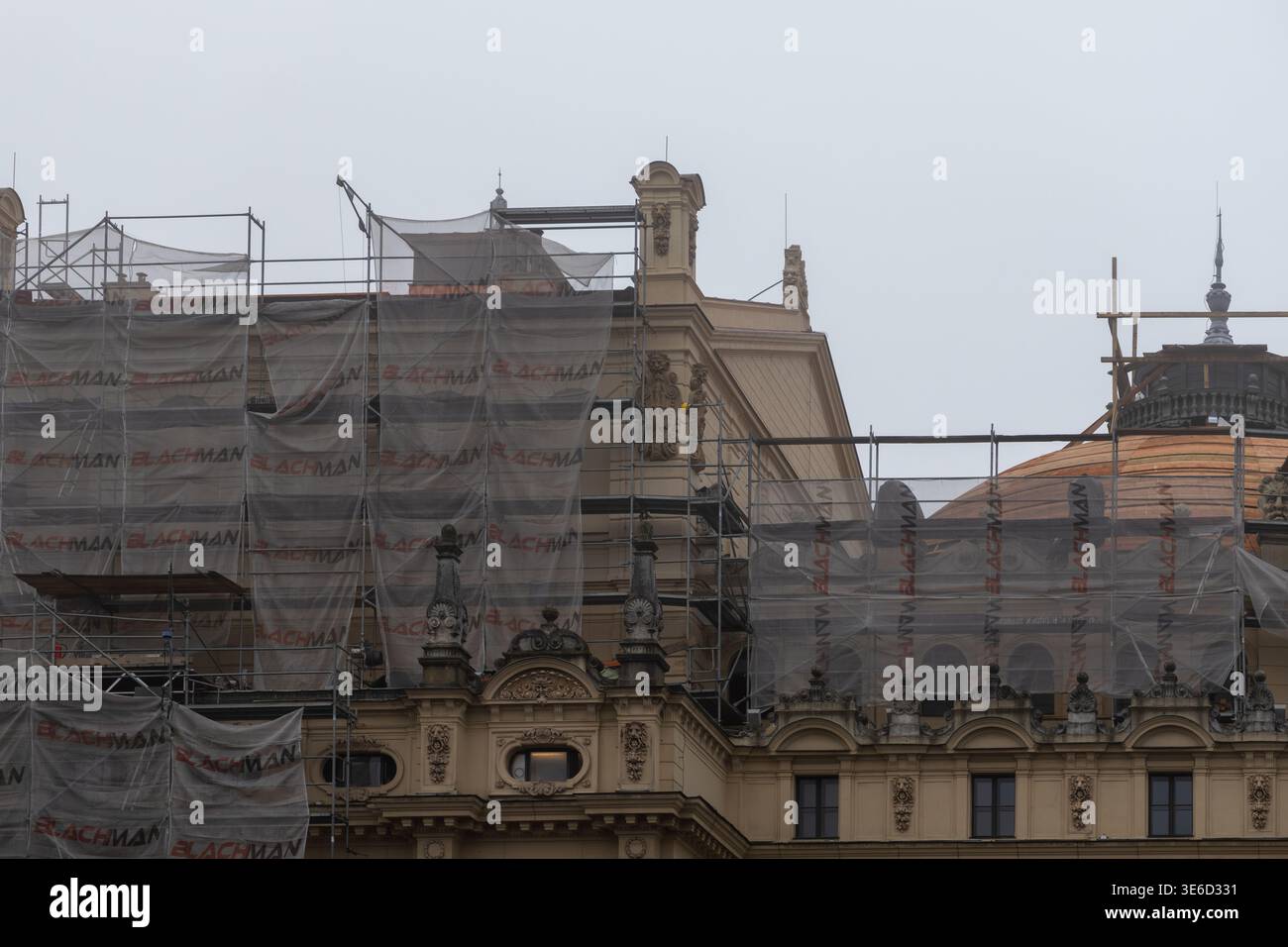 La facciata ornata dell'edificio storico è in fase di ristrutturazione e presenta robuste impalcature in metallo e reti protettive contro un cielo grigio Foto Stock