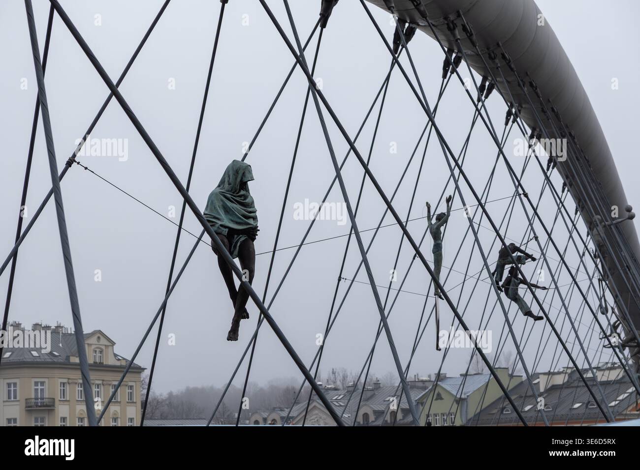 Cracovia, Polonia - 2 dicembre 2025: Le sculture Balancing di Jerzy Kedziora sospese su cavi di ponte simboleggiano l'espressione artistica e il delicato equilibrio Foto Stock
