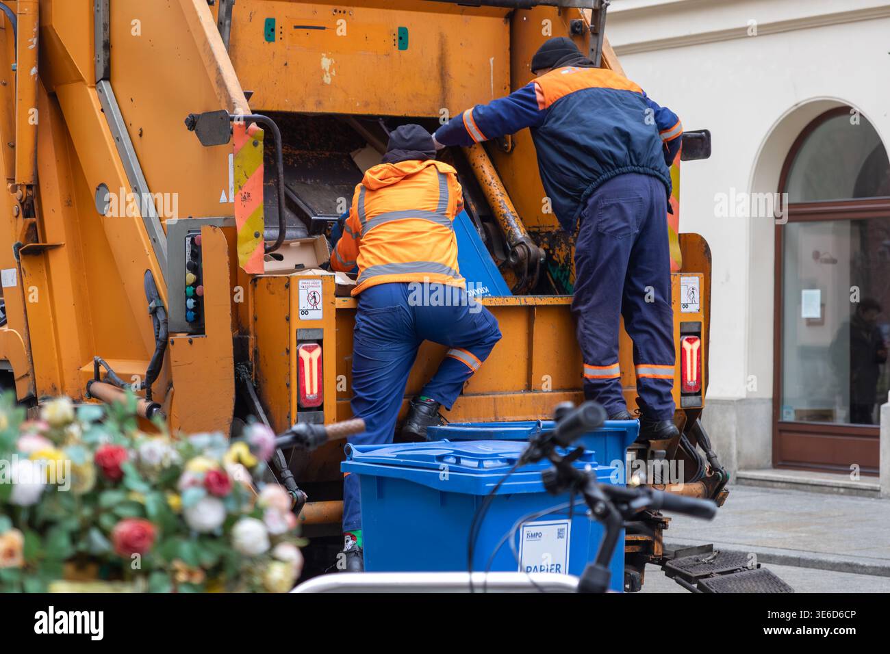 Cracovia, Polonia - 2 dicembre 2025: Gli operatori sanitari urbani trasformano i rifiuti di carta in un camion riciclabile di colore arancione, dimostrando la loro importanza Foto Stock