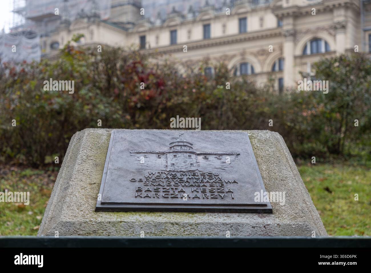 Cracovia, Polonia - 2 dicembre 2025: Targa commemorativa in bronzo raffigurante una torre storica, posta su un piedistallo in pietra all'esterno di un edificio di Cracovia Foto Stock