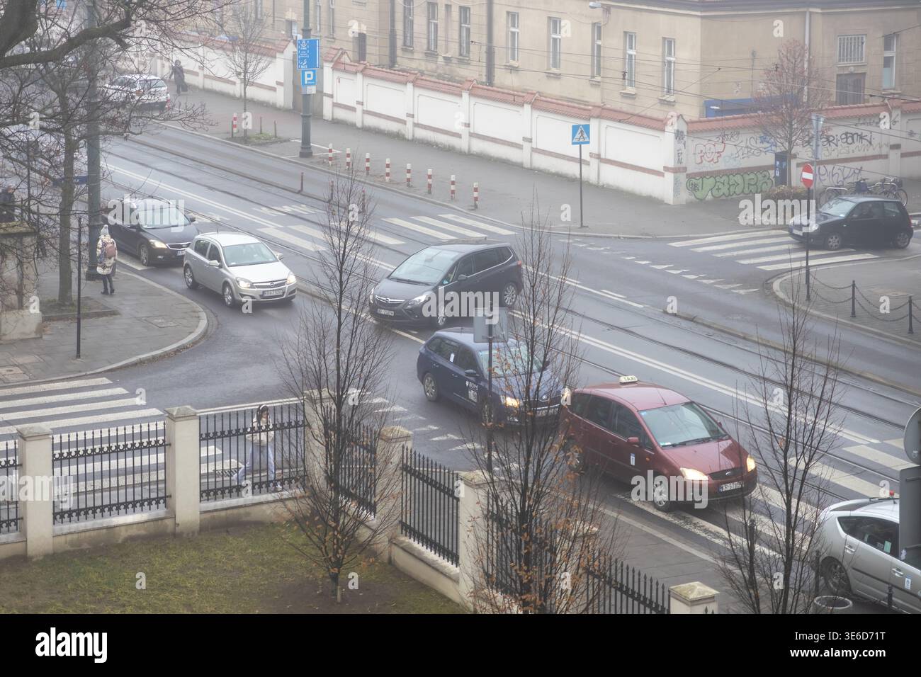 Cracovia, Polonia - 2 dicembre 2025: Vista ad angolo alto di un vivace incrocio stradale cittadino con auto che si muovono su strade bagnate e pedoni che utilizzano l'incrocio Foto Stock