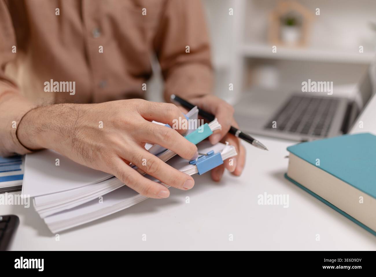 Primo piano di una persona che organizza documenti finanziari con clip sulla scrivania, che rappresenta la gestione della documentazione, il processo contabile, l'organizzazione dell'ufficio e. Foto Stock