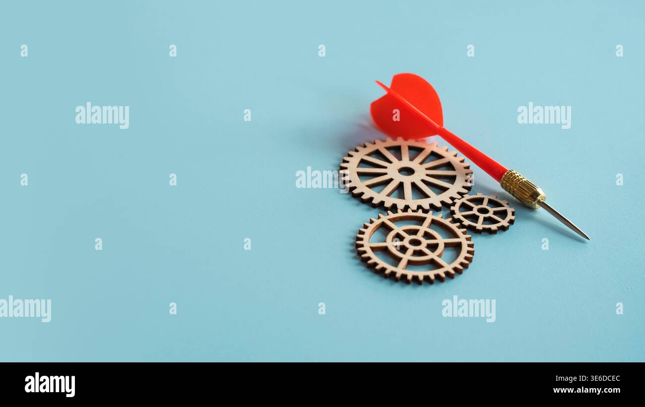 Freccette rosse appoggiate su ingranaggi in legno che simboleggiano la pianificazione strategica e la precisione industriale Foto Stock
