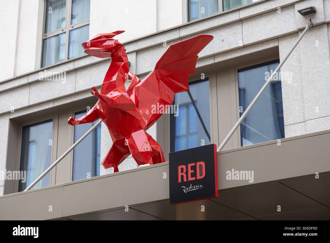 Cracovia, Polonia - 1 dicembre 2025: Una suggestiva scultura rossa del drago poligonale definisce la facciata ROSSA dell'hotel Radisson, trasmettendo il suo design moderno e un Foto Stock