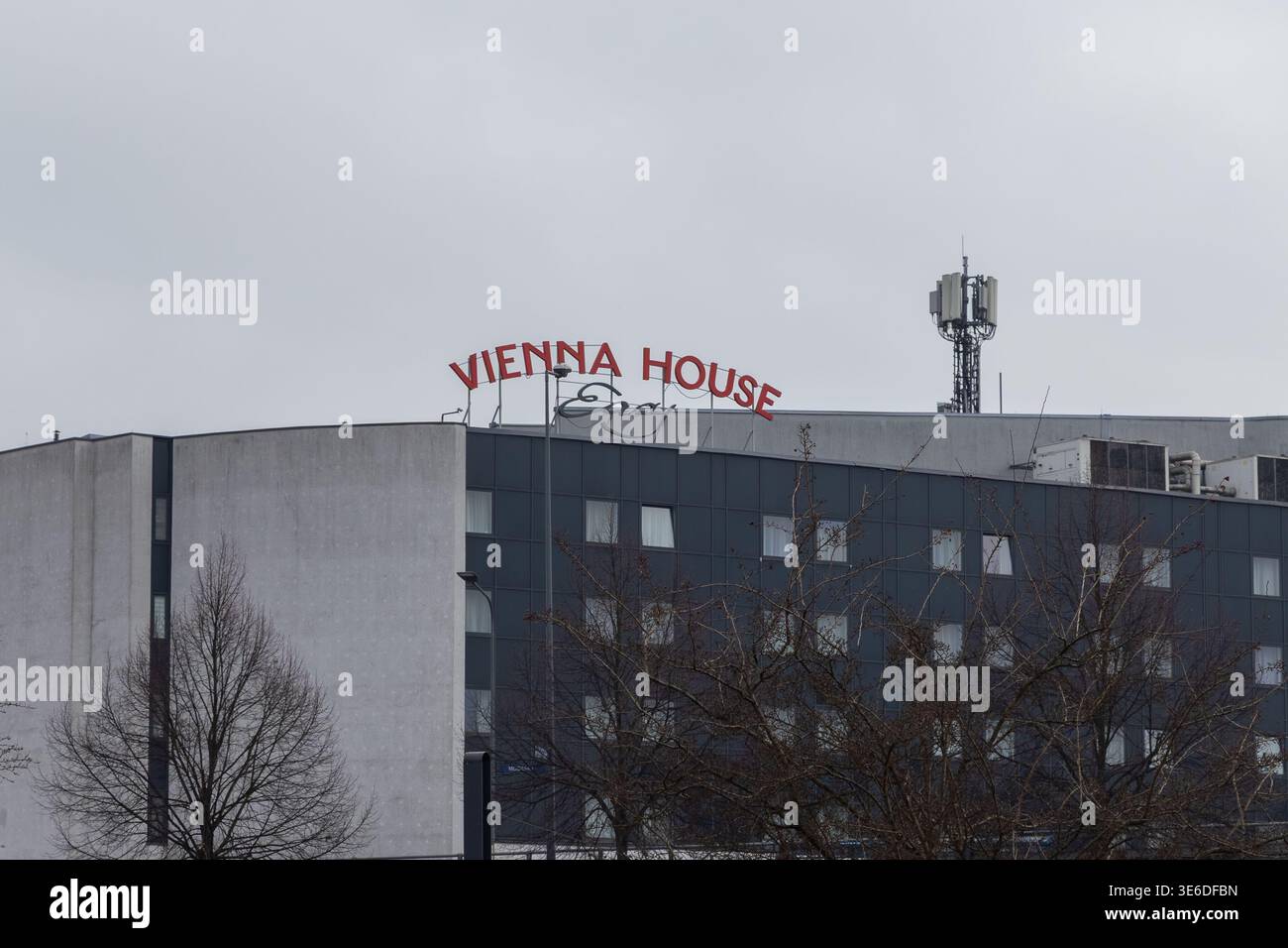 Cracovia, Polonia - 1° dicembre 2025: Facciata dell'hotel VIENNA HOUSE Easy con un'importante insegna rossa e torre cellulare sul tetto sotto il cielo grigio Foto Stock