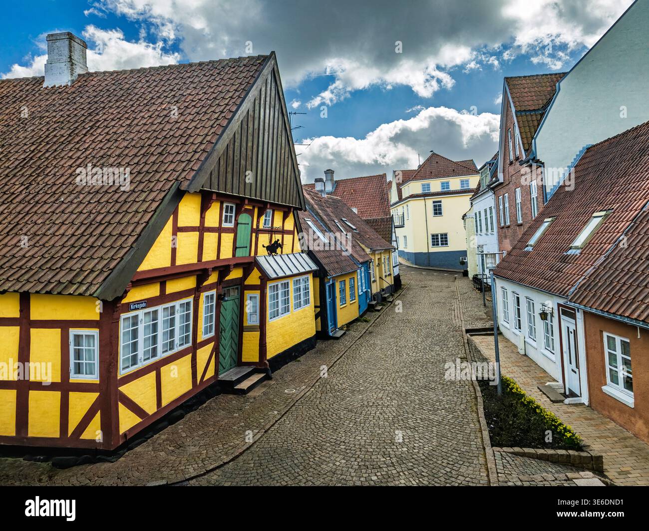 Una tranquilla strada acciottolata fiancheggiata da case colorate a graticcio, ripidi tetti piastrellati e facciate tradizionali in un affascinante villaggio storico europeo Foto Stock
