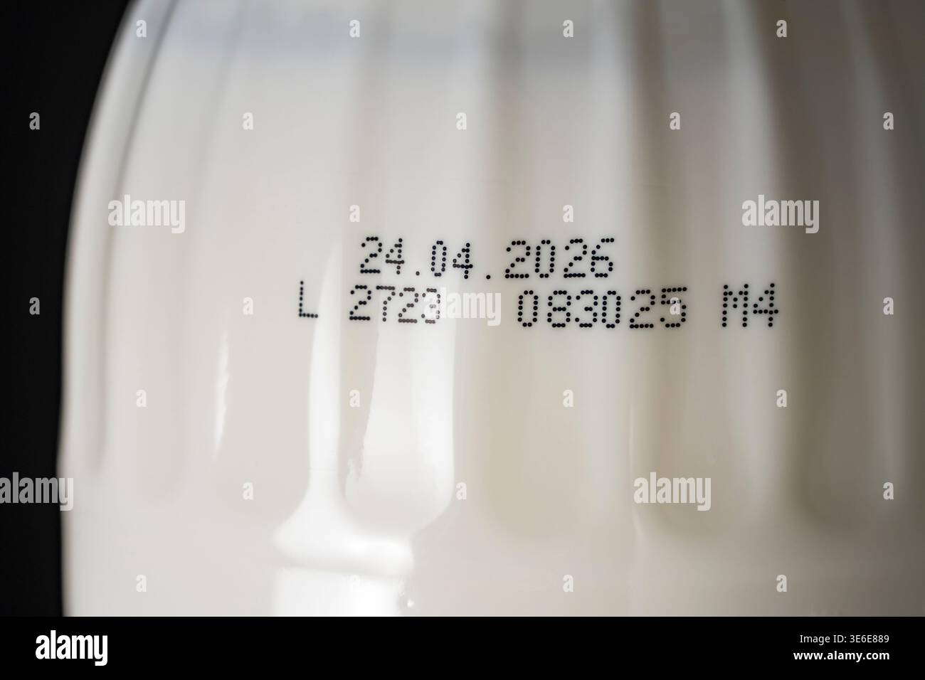 Primo piano della data di scadenza e del codice del lotto stampato su una bottiglia di plastica bianca con prodotto lattiero-caseario. Concetto di freschezza del prodotto, sicurezza alimentare e qual Foto Stock
