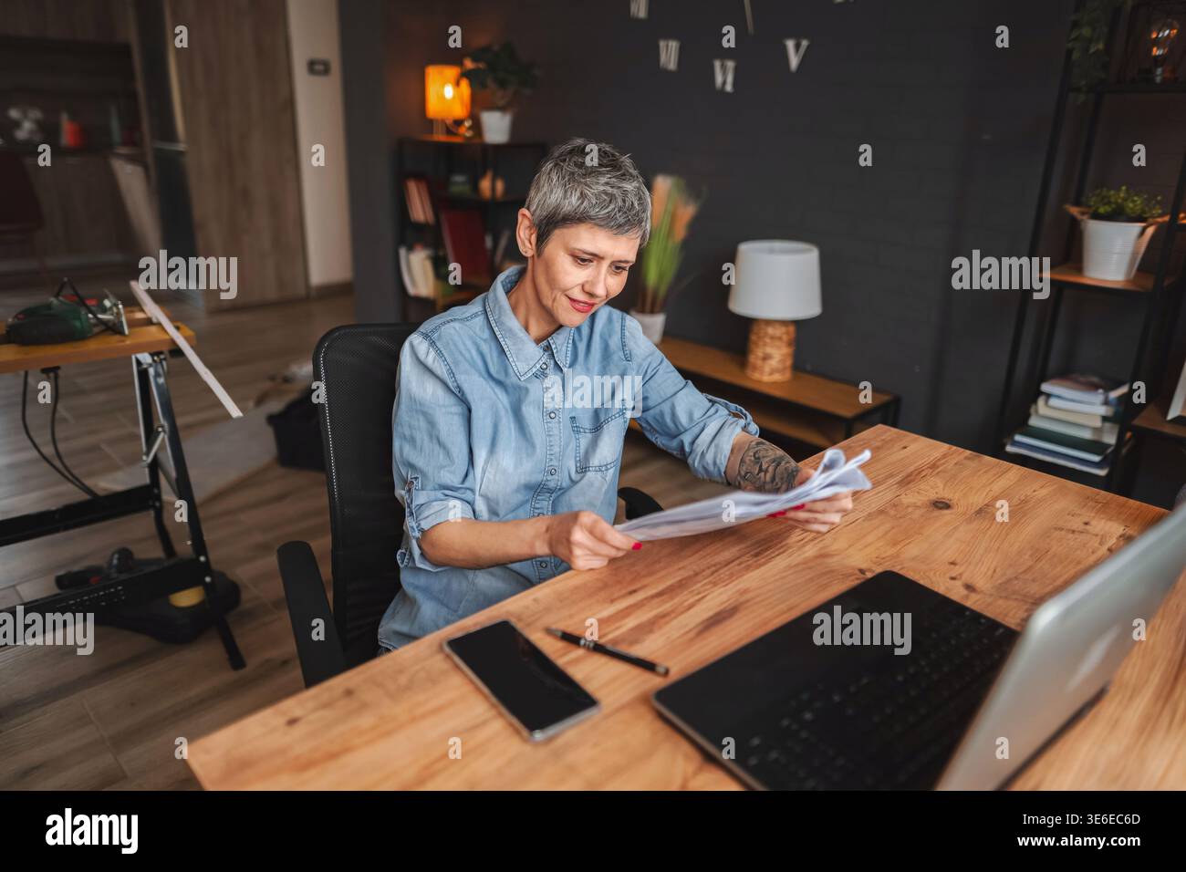 Donna falegname che legge le istruzioni nel suo laboratorio a casa Foto Stock