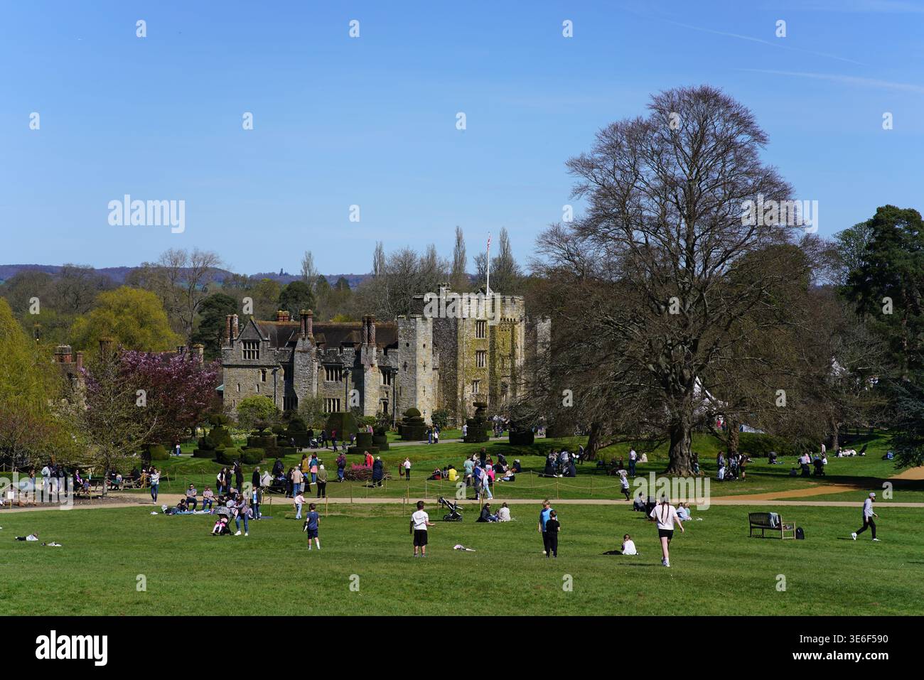 Hever Castle con i visitatori che si rilassano sul soleggiato prato primaverile nei bellissimi giardini storici, Kent, Inghilterra. Hever Castle, Hever, Inghilterra Foto Stock