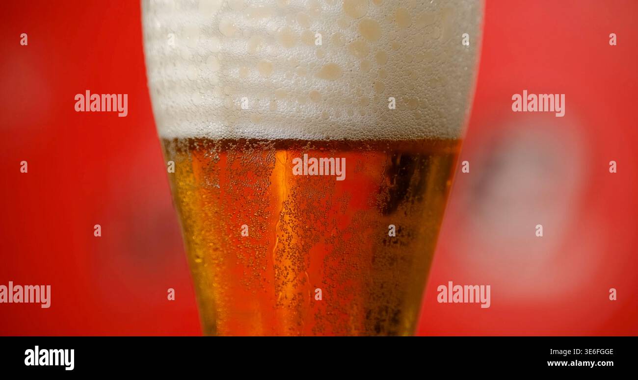 Birra artigianale versata in un bicchiere con schiuma sulla parte superiore servita in un bar durante le ore serali Foto Stock