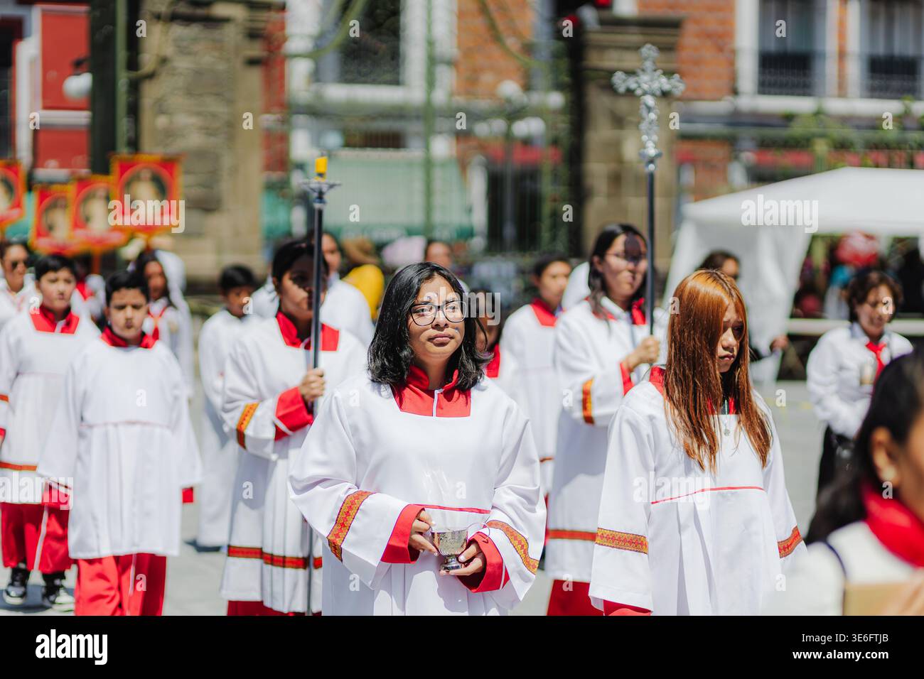 Un gruppo di giovani camerieri d'altare e accoliti vestiti di erba bianca con dettagli rossi partecipa solennemente alla Processione del venerdì Santo Foto Stock