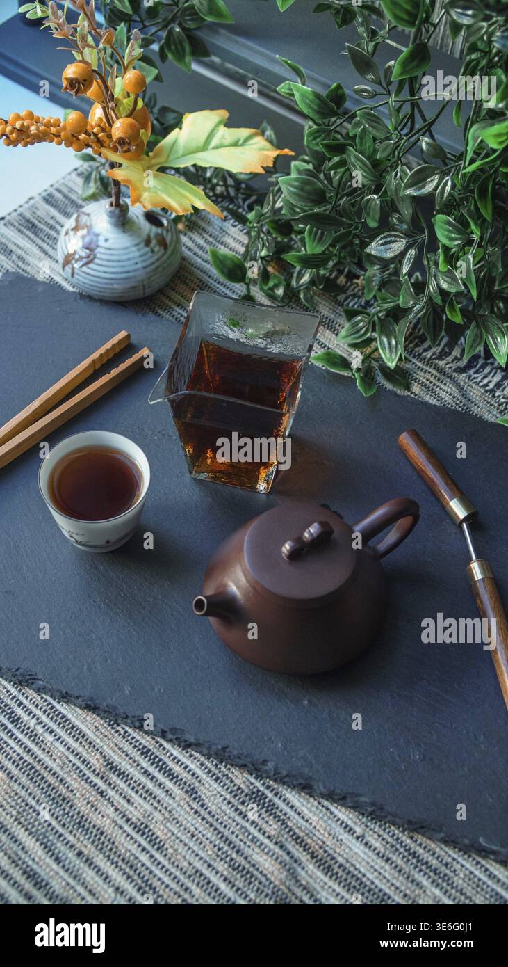 Un ambiente sereno da tè con una bella teiera, tazze eleganti ed elementi naturali per un'atmosfera davvero rilassante Foto Stock