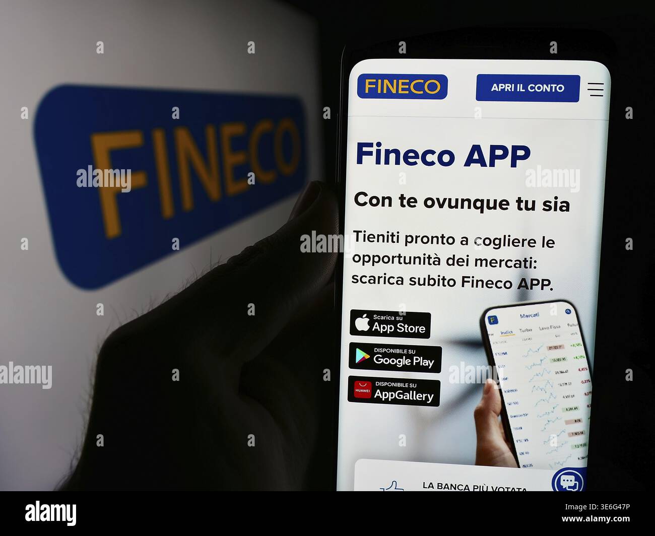 Stoccarda, Germania - 08-12-2024: Persona che detiene cellulare con pagina web della società italiana di servizi finanziari FinecoBank S.p.A. davanti al logo. Concentrati Foto Stock
