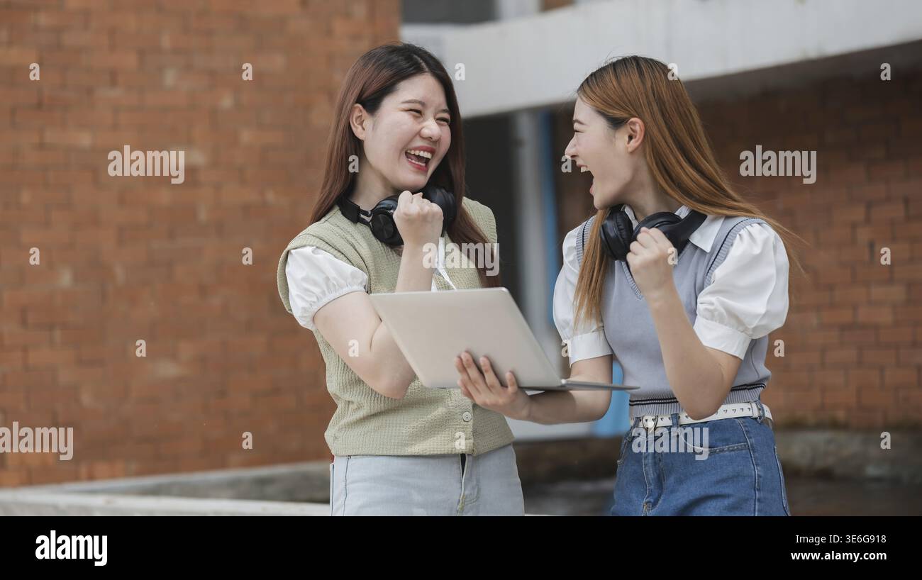 Bella giovane studentessa asiatica con amici all'aperto. Studente universitario che lavora nel campus universitario Foto Stock