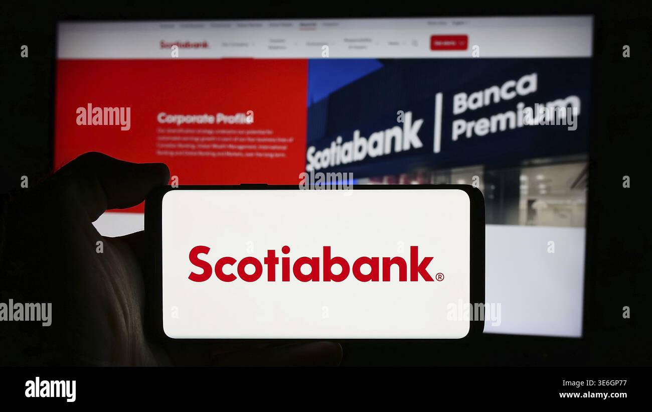 Stoccarda, Germania - 08-12-2024: Persona che detiene il cellulare con il logo della società finanziaria Bank of Nova Scotia (Scotiabank) di fronte alla pagina web aziendale Foto Stock