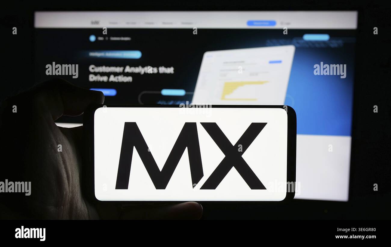 Stoccarda, Germania - 08-28-2024: Persona che detiene il cellulare con il logo della società statunitense di dati fintech MX Technologies Inc. Di fronte alla pagina web aziendale. Focu Foto Stock