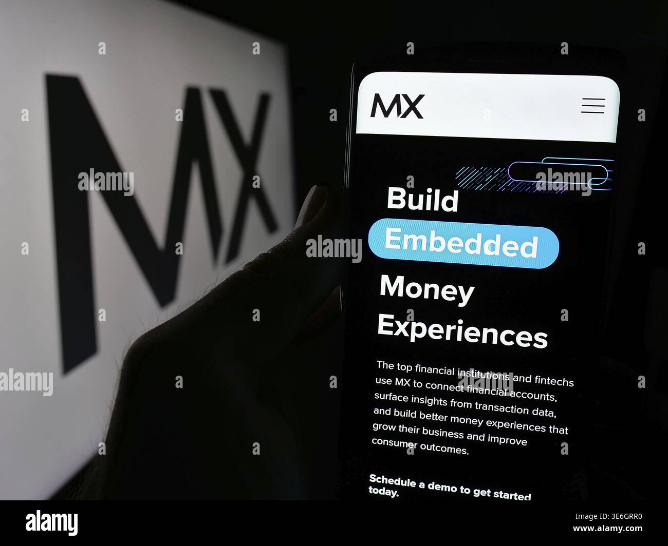 Stoccarda, Germania - 08-28-2024: Persona che detiene il cellulare con pagina web della società statunitense di dati fintech MX Technologies Inc. Davanti al logo. Concentrati sul cent Foto Stock