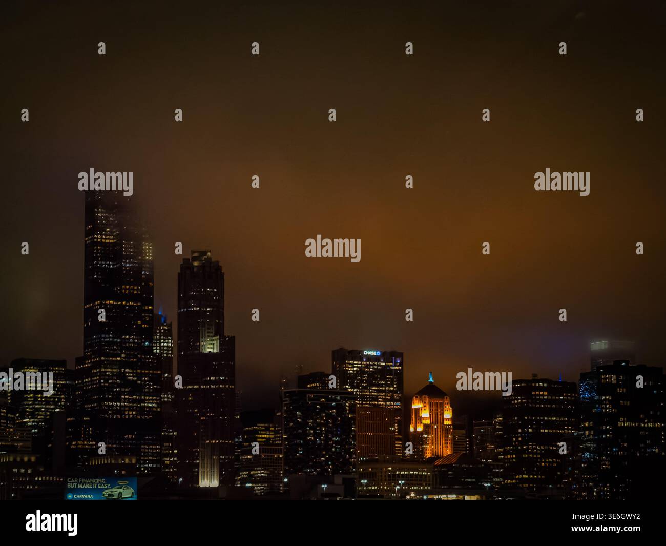 Foggy skyline di Chicago di notte con nuvole arancioni e grattacieli illuminati sul paesaggio urbano del centro Foto Stock