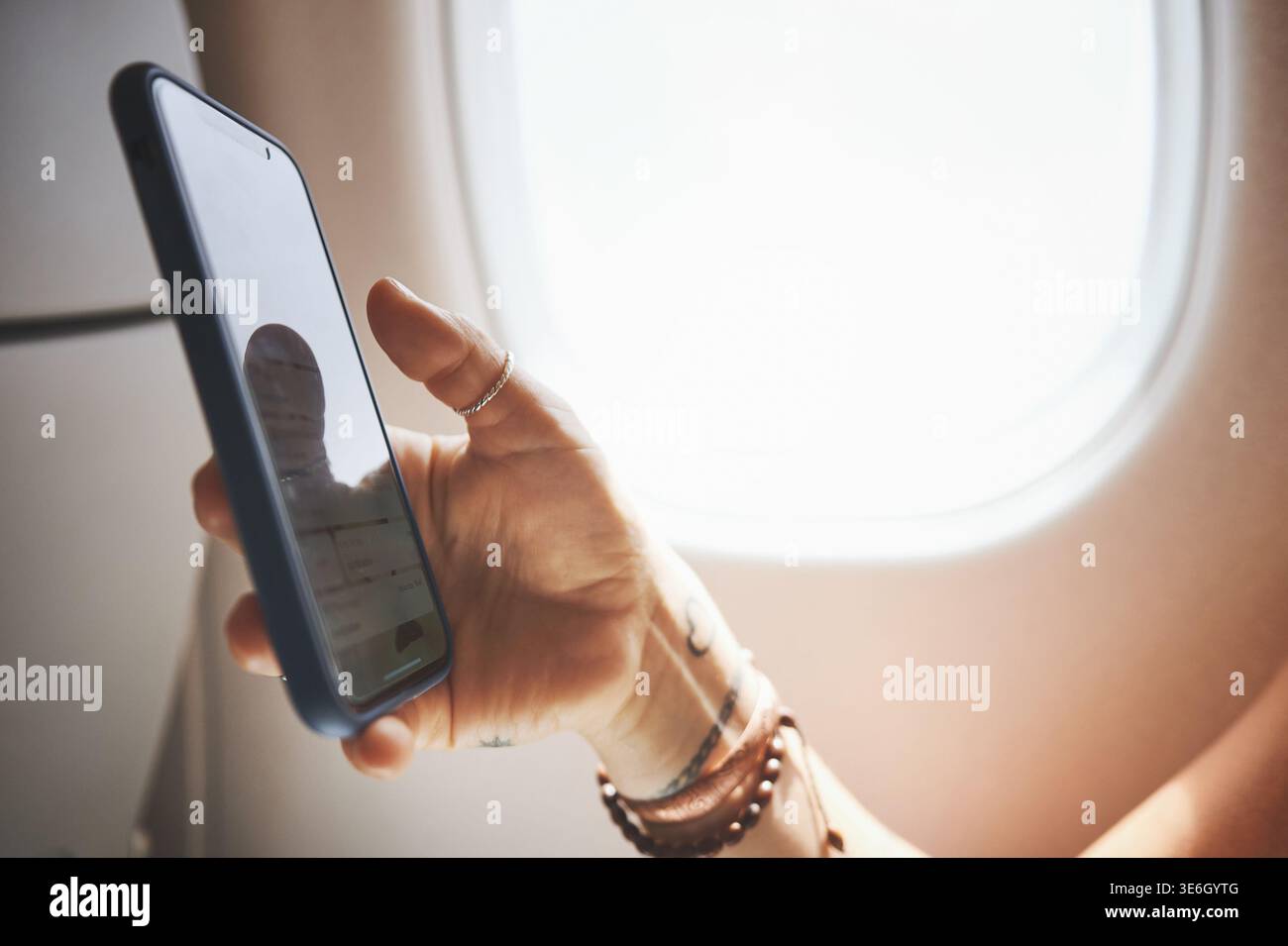 Mani, telefono e persona in aereo per il viaggio, la carta d'imbarco o controllare i dettagli del volo. Trasporto, modalità aereo o passeggeri con dispositivo mobile in cabina Foto Stock