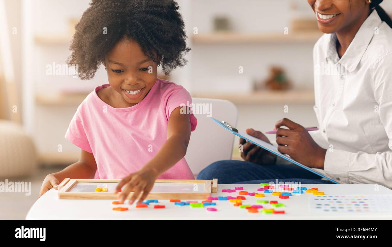 I bambini giocano con forme colorate mentre gli adulti osservano in un ambiente interno luminoso Foto Stock
