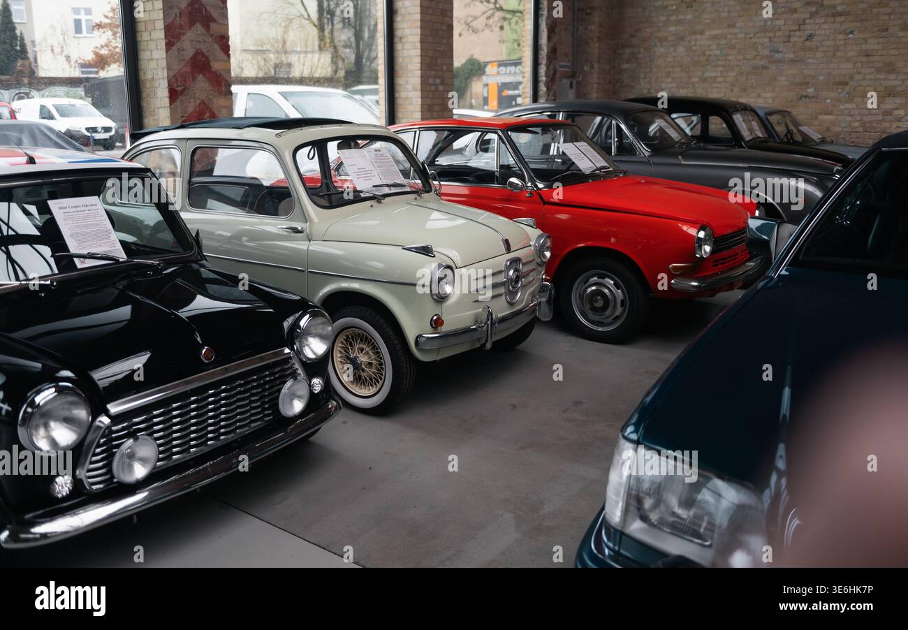 Fila di piccole auto classiche, tra cui Mini Cooper e Fiat 600. Una collezione di iconiche auto compatte d'epoca degli anni '1960, parcheggiate al Classic Remise di Berlino. Foto Stock