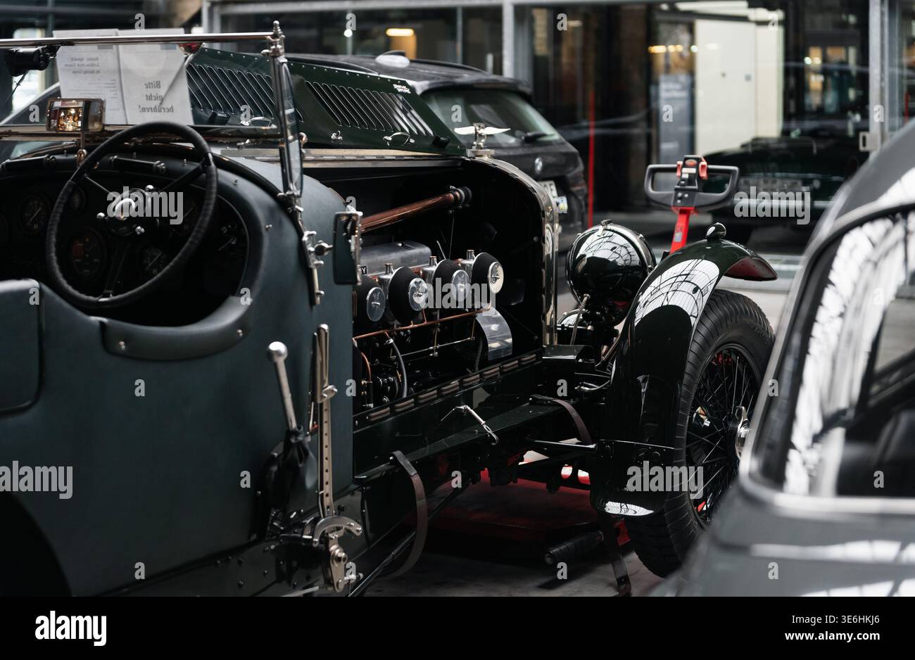 Bentley Speed 8 con motore a otto cilindri in linea esposto in officina. Bentley Tourer vintage verde scuro con ruote in filo metallico e cabina di pilotaggio retrò con cofano aperto. Foto Stock
