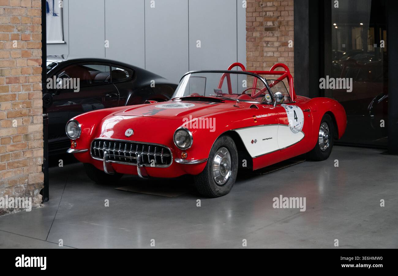 Auto da corsa Corvette C1 classica rossa e bianca nel garage. Vista frontale di tre quarti della Chevrolet Corvette Roadster 1957 con roll bar rosso. Foto Stock