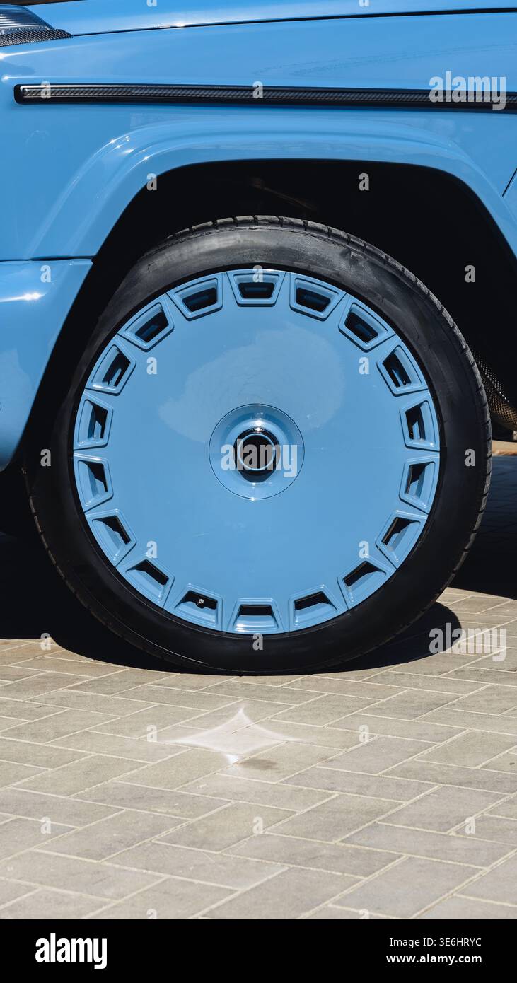 Ruota blu brillante su un veicolo parcheggiato in un'area asfaltata alla luce del giorno Foto Stock
