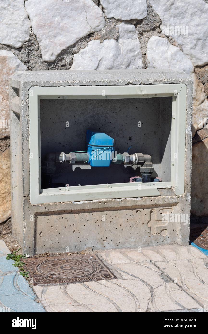 Misuratore dell'acqua installato in un armadio in calcestruzzo che misura il consumo di acqua residenziale Foto Stock