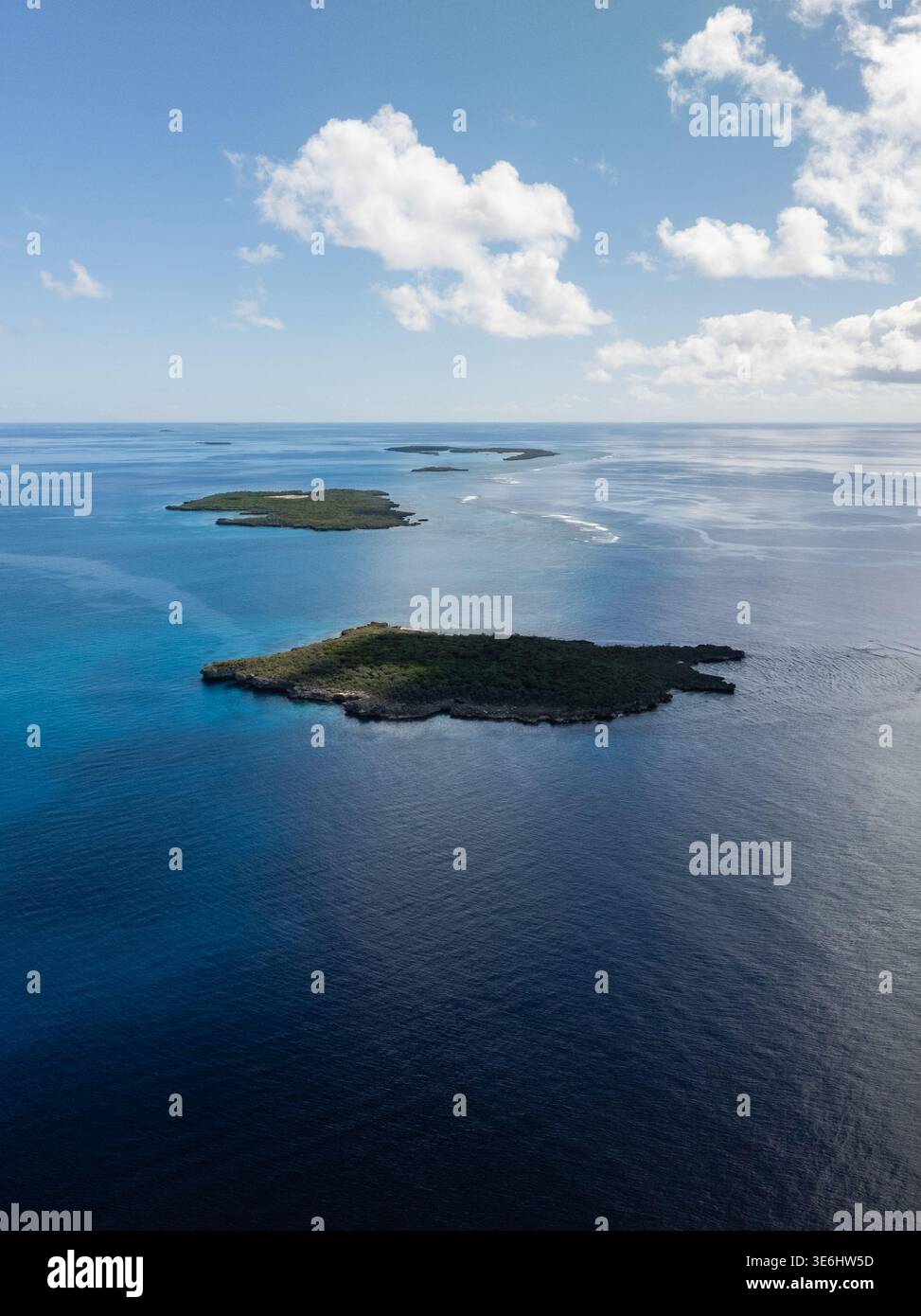 Veduta aerea delle piccole isole sparse attraverso il mare blu profondo, contrastando con il cielo luminoso e le nuvole sparse, Ouvéa, provincia delle Isole Loyalty Foto Stock