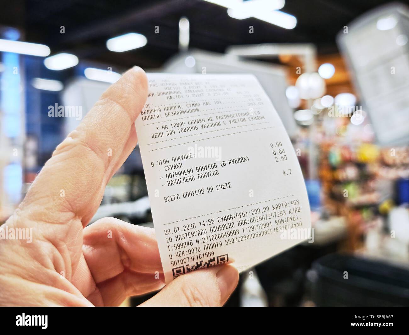 Kirov, Russia - 29 gennaio 2026: Il cliente in negozio conserva una ricevuta che indica l'importo totale pagato per gli articoli alimentari, mostrando le spese dei consumatori e i pur Foto Stock