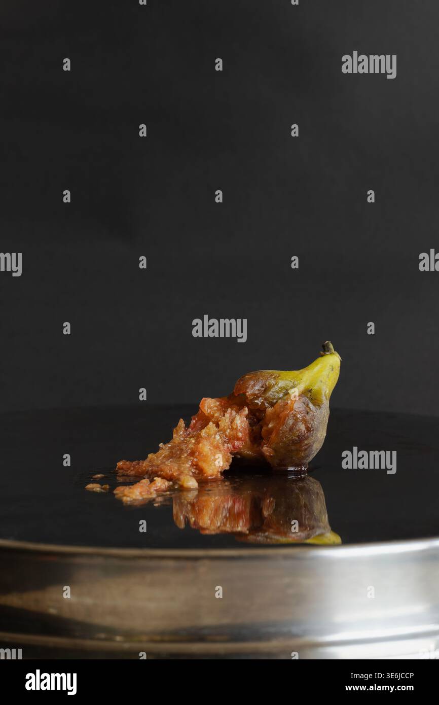 Fico maturo su un piatto argentato riflettente su uno sfondo scuro. Cibo moderno e suggestivo, natura morta che si adatta alla tendenza romantica Vamp. Foto Stock