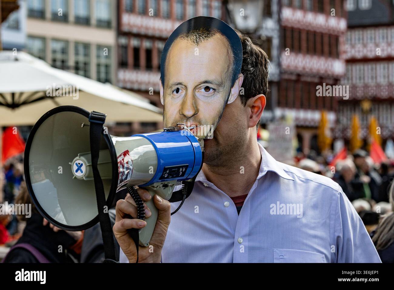 Manifestante che indossa 'Friedrich-Merz-Mask' e parla attraverso il megafono durante la dimostrazione "Schulstreik gegen Wehrpflicht" a Francoforte, Germania. Foto Stock