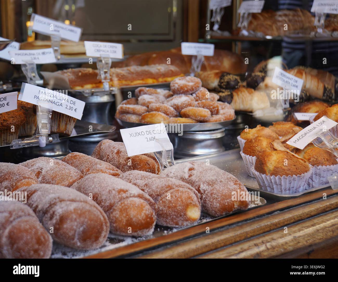 Vista intima dalla strada attraverso la vecchia finestra incorniciata in legno di panetteria, pane, pasticcini e dolcetti in mostra. Foto Stock