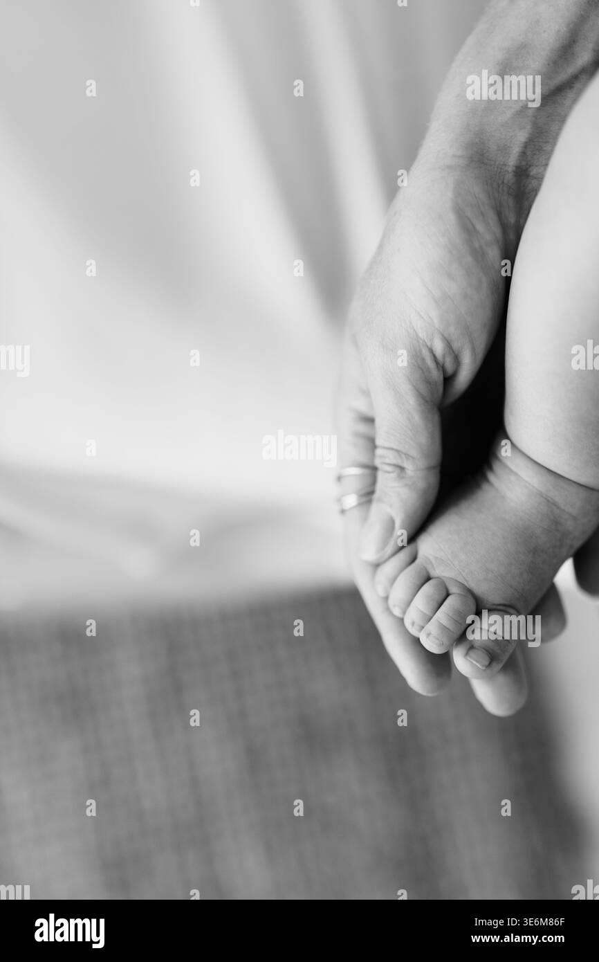 Vista ravvicinata della mano di un adulto che tiene le dita fragili del neonato in pace Foto Stock
