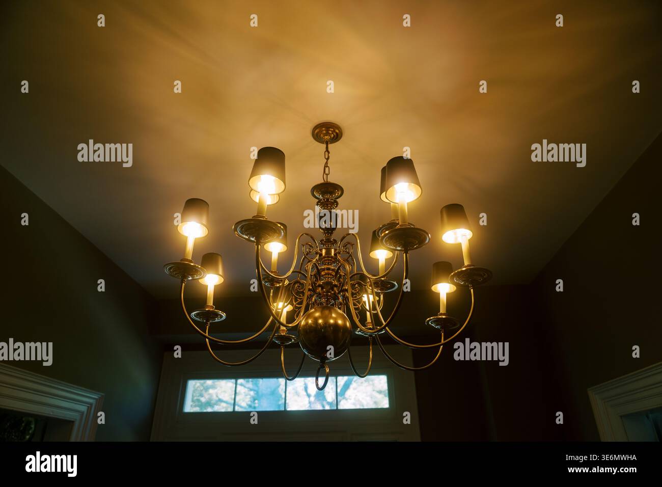 Charming Brass Chandelier offre un'illuminazione soffusa in un ambiente accogliente Foto Stock