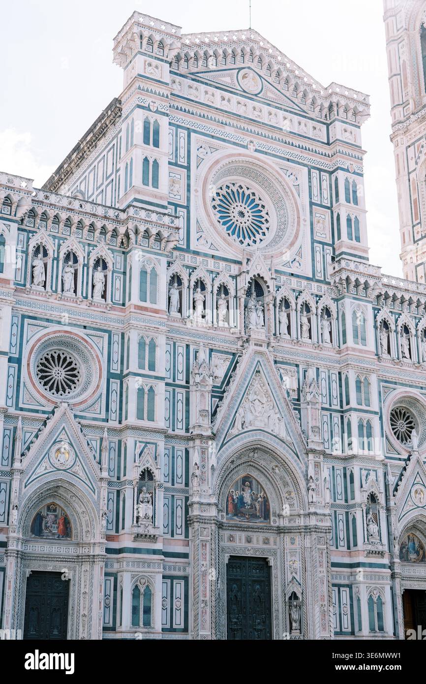 La facciata della cattedrale illuminata dal sole mostra il design dettagliato delle finestre floreali e la simmetria Foto Stock