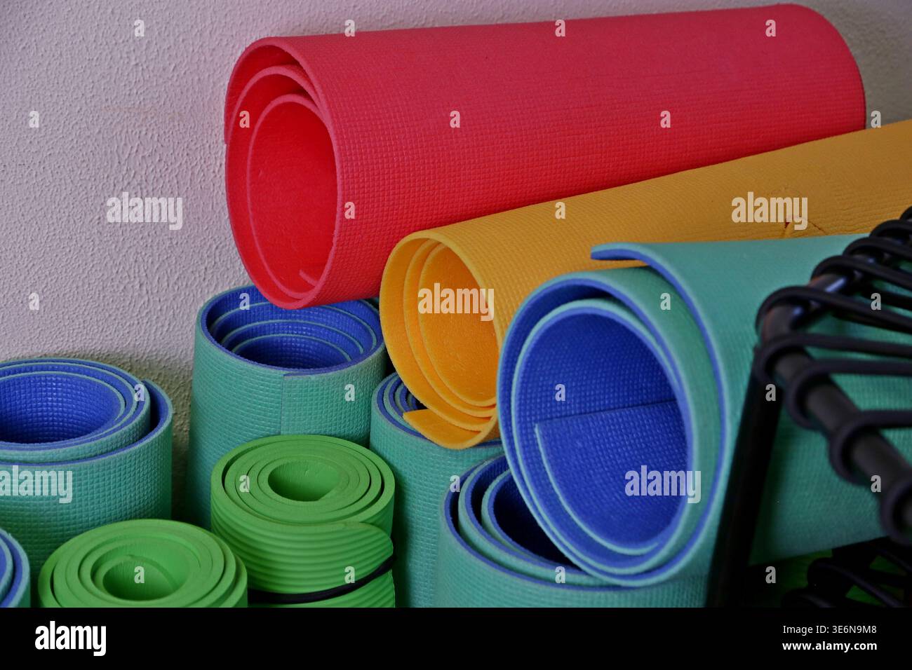 I tappetini da yoga in diversi colori sono impilati in una sala fitness. Sono preparati per le lezioni e l'uso personale da parte di studenti e insegnanti. I tappetini presentano forme e dimensioni diverse. Foto Stock