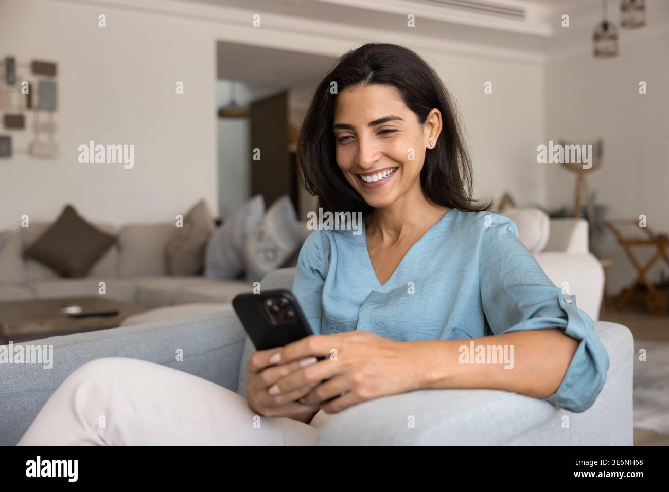 Donna sorridente mentre legge un messaggio o guarda contenuti sullo smartphone Foto Stock
