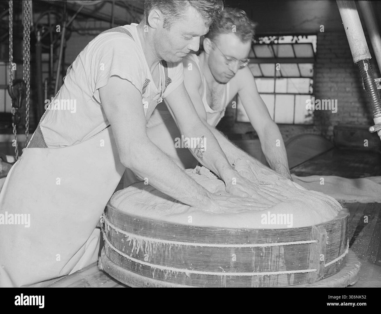 I lavoratori che premono la cagliata negli stampi durante la produzione di formaggio svizzero all'interno di uno stabilimento di Madison, Wisconsin, fotografato da John Vachon. Foto Stock
