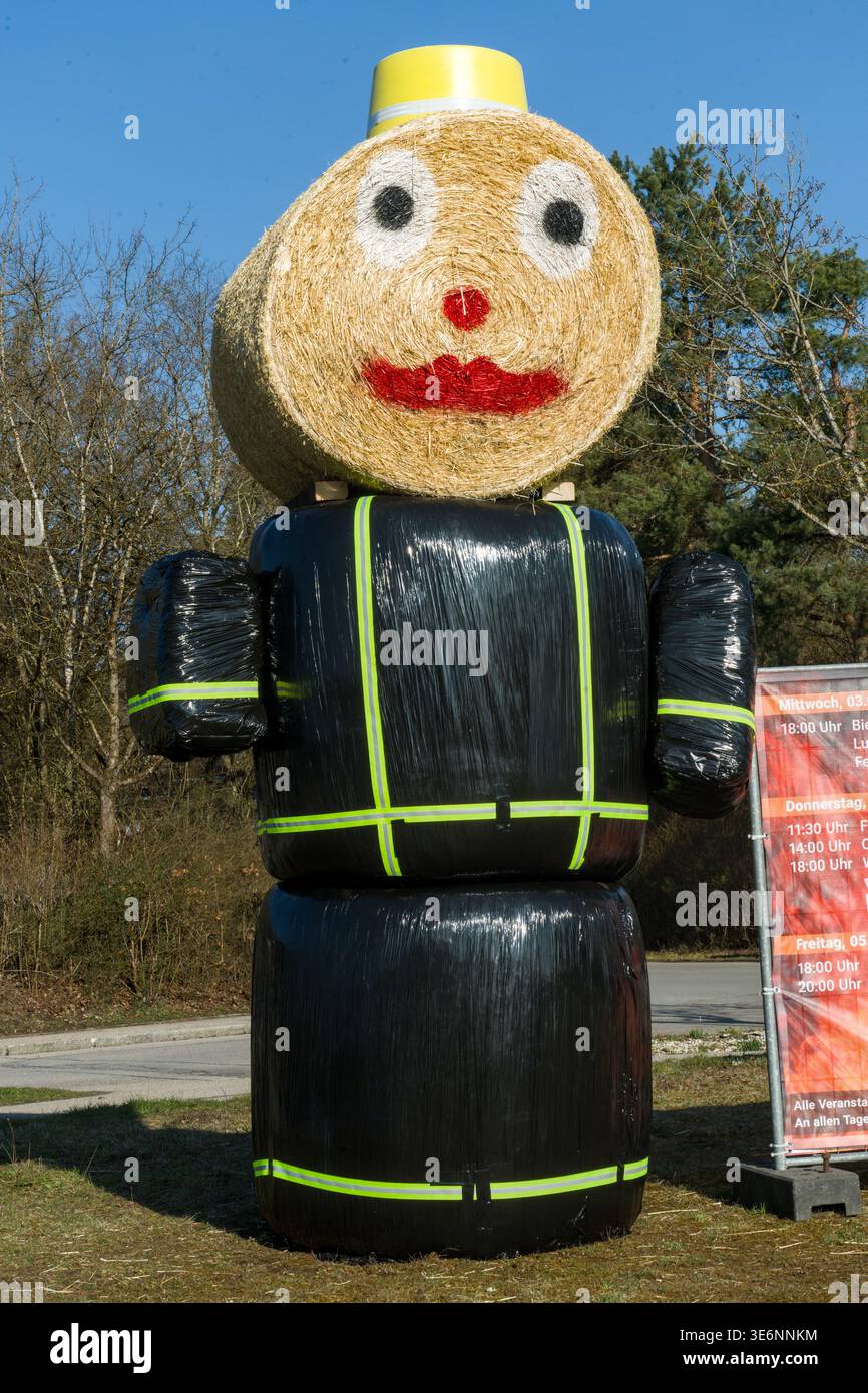 Grande figura di paglia con faccia amichevole e dettagli neri e gialli nel paesaggio rurale, Taufkirchen, Baviera, Germania Foto Stock