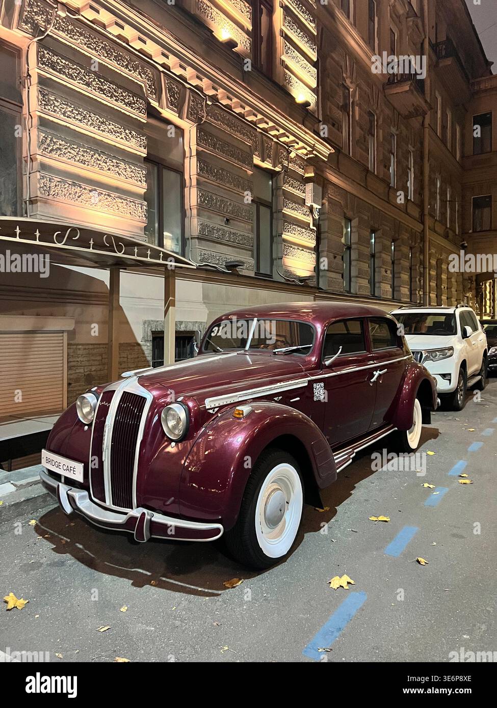 Berlina borgogna d'epoca parcheggiata in una strada stretta di notte nel centro di San Pietroburgo, Russia. - Immagine stock catturata con smartphone