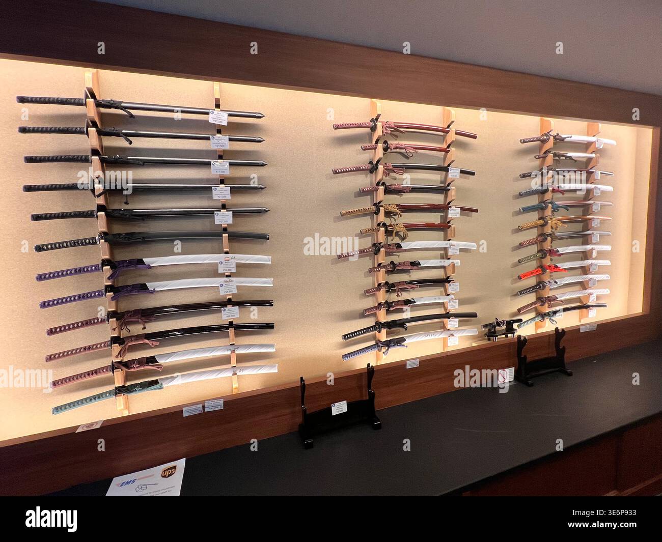 Esposizione di spade giapponesi montate su una parete all'interno di uno spazio espositivo interno a Kyoto, Giappone. - Immagine stock catturata con smartphone